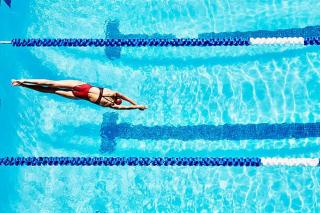 Umělecká fotografie Female competitive swimmer diving into pool, Thomas Barwick,